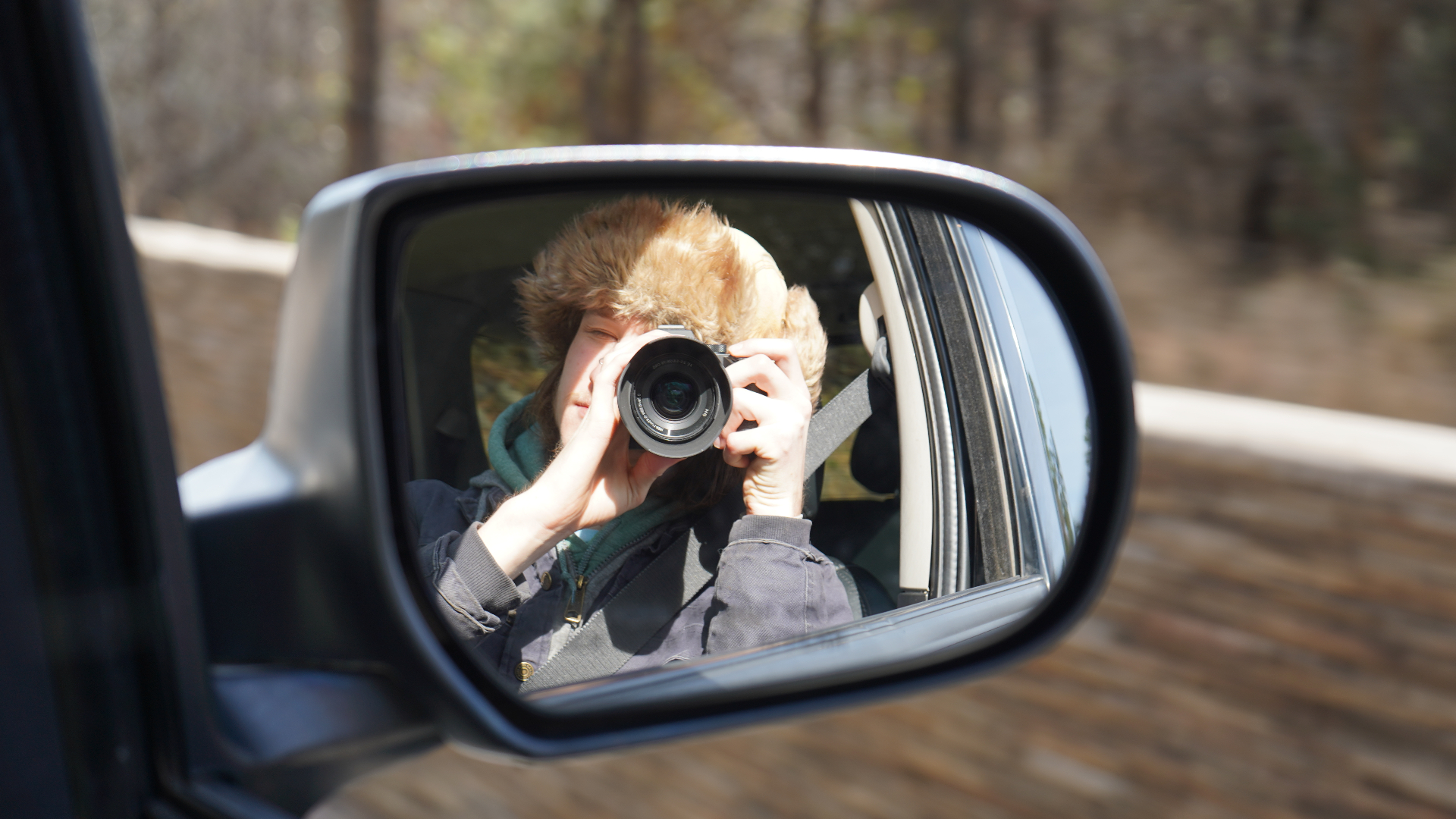 Seth Sherman taking a photo in a car side mirror
